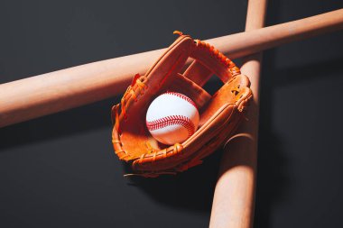 Baharatlı deri bir beyzbol eldivenini gösteren detaylı bir manzara el değmemiş bir topu, deneyimli ahşap bir sopayla bastırılmış bir arka fona yerleştiren.