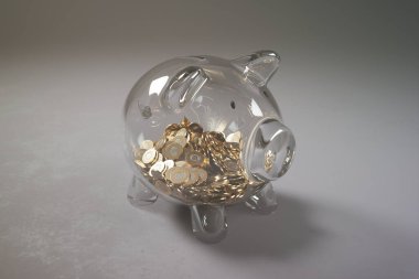 Altın sikkelerle dolup taşan şeffaf bir domuz kumbarası, finansal büyüme, yatırım stratejileri ve çarpıcı bir grafikle tasarruf yapmanın önemini gösteren bir örnek..
