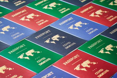 Bir masaya yayılmış çeşitli COVID-19 dokunulmazlık pasaportları koleksiyonu, uluslararası sağlık ve seyahat belgelerindeki yeni normalin somut bir örneği..