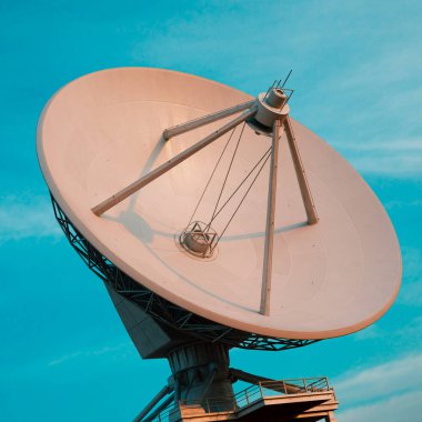 Entellektüel bir uydu anteni, berrak mavi gökyüzünün dingin arkaplanına güvenle dayanır. Parlak yapısı, güneş ışınlarının yumuşak sıcaklığı tarafından öpülmüştür..