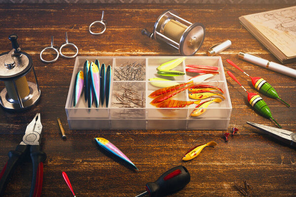 Close-up view of a diverse fishing tackle collection spread on a weathered wooden table, featuring an assortment of multicolored lures and angling equipment.