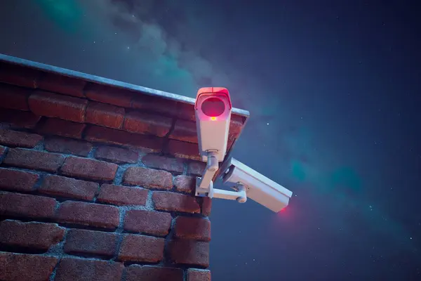 High-tech security camera affixed to an old brick wall, keenly observes under a celestial night sky, offering a blend of antiquity and modern surveillance.