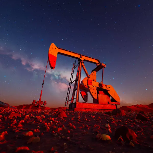 エネルギー生産の連続サイクルを象徴する 上記の星の輝きによって打ち砕かれたシルエットのオイルポンプジャックの印象的なシーン — ストック写真