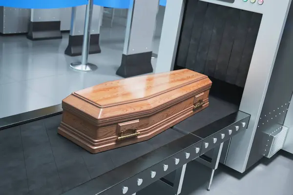 洗練された木製棺で 洗練された葬儀サービス施設内のコンベアシステムに装着した金属製のハンドルで 厳粛さと職人技を反映しています — ストック写真