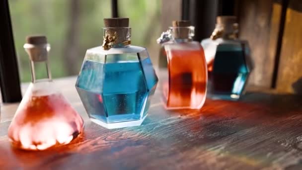 一排装饰玻璃瓶 盛满了生机勃勃的彩色液体 陈列在乡村木制桌面上 由自然光照亮 — 图库视频影像