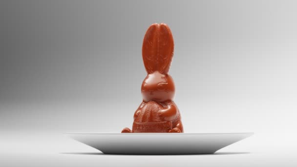 Stiliserad Chokladkaninskulptur Äts Centralt Placerad Vit Platta Mot Lutning Bakgrund — Stockvideo