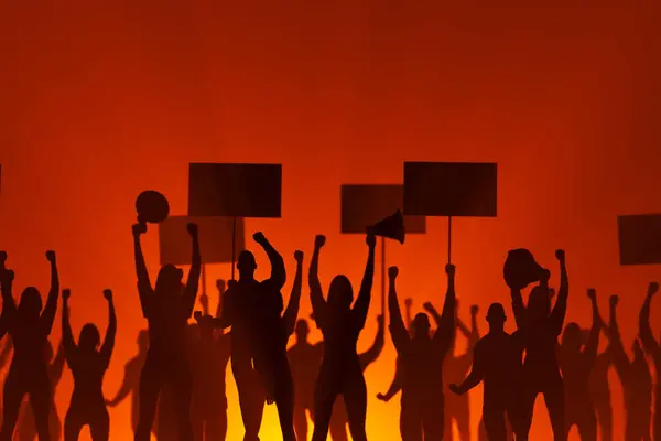 黄昏的时候 轮廓分明的人物举着标志 举起拳头 这有力地象征着对权利和自由的抗议 他们的声音在橙色天空中的扩音器中被放大了 — 图库照片