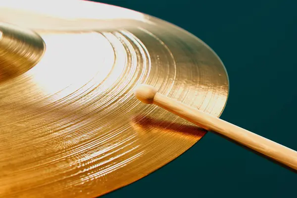 この画像は 輝く真鍮シンバルとの接触を作る木製のドラムスティックの動的作用を凍結し 音楽制作におけるテクスチャとエネルギーを強調しています — ストック写真