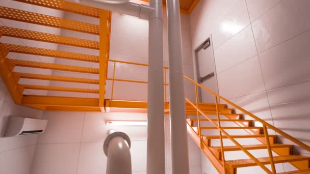 Widok Nowoczesne Wnętrze Budynku Żywymi Pomarańczowymi Schodami Przemysłowymi Białymi Rurami — Wideo stockowe