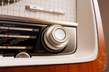 Bu görüntü klasik ahşap bir radyoyu ayrıntılı bir şekilde yakalar. Akort kadranını, ses düğmesini ve hoparlörünün üzerindeki klasik tekstil kapağını vurgular..