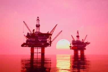 Göz kamaştırıcı bir gün batımına karşı siluetlenmiş deniz aşırı petrol kulesinin büyüleyici görüntüsü, yapıları aşağıdaki sakin denizde yansıyor..