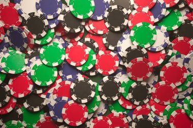 Kumarhane ve kumar ortamlarındaki canlılığı ve riski sembolize eden dağınık renkli kumarhane çiplerine ilgi çekici bir bakış açısı..