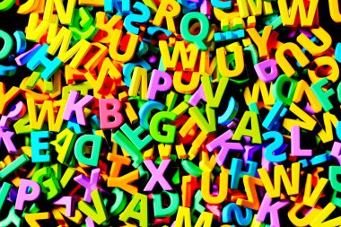 Bu resim, çeşitli yönelimlerde üç boyutlu plastik alfabe harflerinden oluşan canlı, dağınık bir koleksiyon yakalar, parlak ve çekici renkler dizisini gösterir..