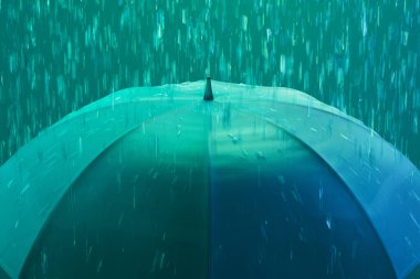 Yaratıcı bir anı yakalayan bu resim, bir şemsiye üzerine çağlayan canlı bir deniz mavisi yağmurunu tasvir ediyor, soyut bir zemin üzerine kurulmuş, gizemli bir aurayı anımsatıyor..