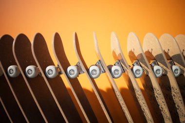 Canlı turuncu bir arka plan tarafından vurgulanan, özgün dokuları ve paten kültürünün dinamik çekiciliğini vurgulayan düzenli bir kaykay koleksiyonu..