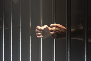 Bu görüntü, hapishanenin soğuk ve affetmeyen demir parmaklıklarını sımsıkı tutarak özgürlüğün kaybını sembolize eden, hapisteki umutsuzluğu yakalıyor..