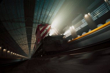 Yüksek hızlı kırmızı bir ekspres tren, yıldızlı bir gökyüzünün altındaki gece istasyonunda bulanıklaşır, hızlı bir hareket hissi uyandırır ve modern yolculuğun heyecanı.