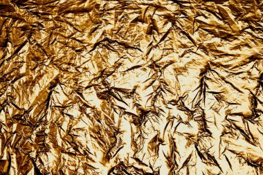 Bu resim, çeşitli kullanımlar için elverişli lüks ve yüksek desenli metalik bir yüzey sunan kırışık altın folyo üzerinde karmaşık kıvrımlar ve ışık oyunlarını yakalar..