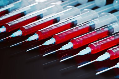 Kırmızı sıvıyla dolu birden fazla şırınganın ilgi çekici bir görüntüsü, karanlık, yansıtıcı bir arka plan üzerine kurulmuş, tıbbi araştırma, sağlık ve tedavi temaları çağrıştırıyor.