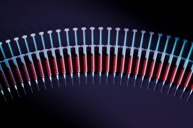 Kırmızı aşı sıvısıyla dolu tıbbi şırıngalar, gölgeli bir yüzeye titizlikle yerleştirilmiş, hastalık önleme ve tedavi araştırmalarındaki gelişmeleri vurguluyor..