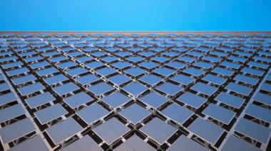 Açık mavi gökyüzüne karşı geniş bir güneş panelinin alçak açılı görüntüsü. Geometrik desen ve yansıtıcı yüzeyler temiz enerji teknolojisini vurguluyor.