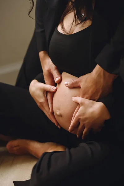 穿着黑色西服的孕妇和丈夫手拉手在怀孕的肚子上 爱的概念 家庭观念快乐生儿育女的概念 — 图库照片