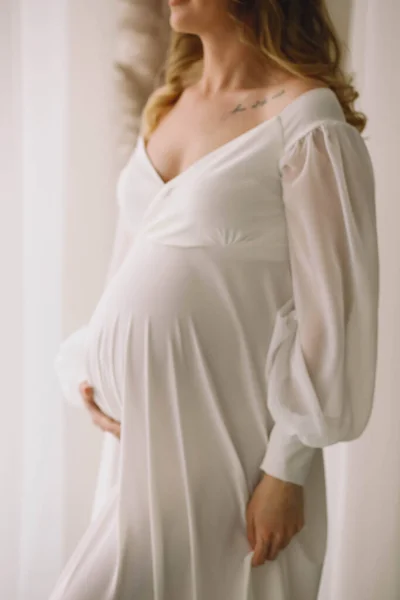 Kobieta Ciąży Stylowej Białej Sukience Trzymając Jej Brzuch Pozowanie Studio — Zdjęcie stockowe