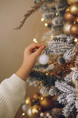 Çocukların yakın çekilen fotoğrafı süslenmiş Noel ağacına karşı beyaz bir Noel balosu tutuyor. Noel ve Yeni Yıl Aile Kutlama Konsepti