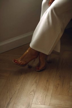 Beyaz pantolonlu ve şeffaf topuklu seksi bir kadının bacaklarını yakın çekimde çek. Uzayı metin için kopyala. Güzel kadın bacakları. Duvar kağıdı ya da baskı dergisi için iyidir.