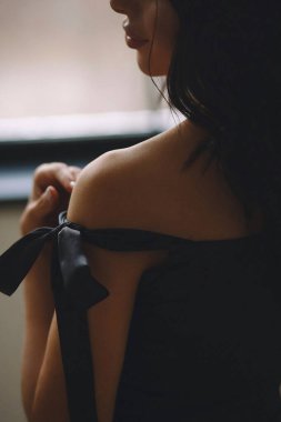 Stüdyoda, siyah elbise giymiş çekici bir esmer kadının kayışı baştan çıkarıcı bir şekilde omzundan çıkarması. Güzellik ve moda