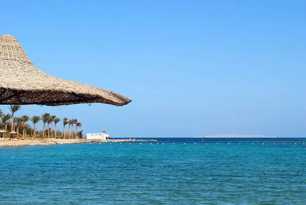 Hurghada 'da Kızıldeniz kıyısında palmiye ağaçları olan güneşli bir tatil köyü. Plaj, Mısır. Seyahat konsepti ve fikri. Metin için alanı kopyala