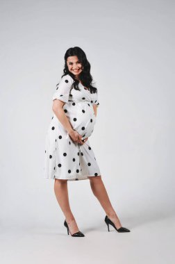 Beyaz benekli elbise giyen, beyaz tenli, esmer, çekici bir kadının stüdyo portresi. Uzayı metin için kopyala. Duvar kağıdı ya da baskı dergisi için iyidir. 