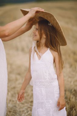Anne sahada kızına hasır şapka takıyor. Yaz fotoshoklama. Yaz sezonu. Mutlu annelik kavramı. Yaz tatili
