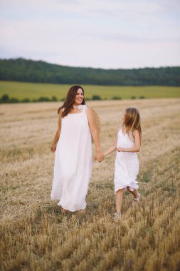 Sahada koşan yazlık elbiseli mutlu anne ve kız. Mutlu annelik kavramı. Yaz fotoshoklama. Yaz tatili. Metin için boşluk