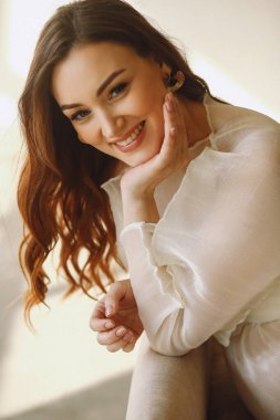 Havalı fildişi elbiseler içinde gülümseyen hamile bir kadının portresi. Güzellik ve moda