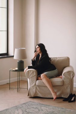 Siyah ceketli ve mavi gecelikli güzel esmer kadın sandalyede oturuyor ve stüdyoda poz verirken elinde parfüm tutuyordu. Uzayı metin için kopyala. Rahatlama zamanı. İş kadını