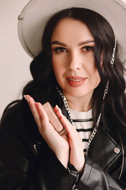 Beyaz şapkalı, elinde tonal krem tutan güzel esmer makyaj sanatçısı portresi. Güzellik ve moda