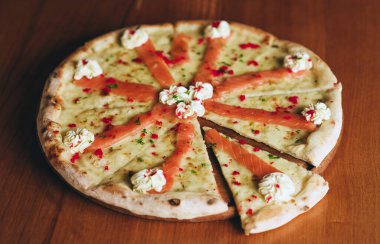 Parlak renklerde lezzetli somon pizzası. Somon ve peynirli pizza. Tahta masada füme somonlu pizza.