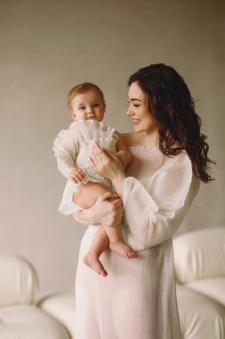 Aile görünüşü. Anne kızını kollarında tutuyor. Anne ve bebek aynı elbiseyi giyiyor. Mutlu annelik kavramı