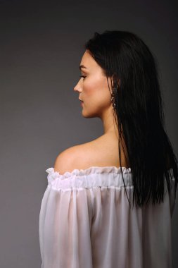 Genç ve güzel esmer bayanın arka manzara stüdyo portresi. Doğal makyaj ve saç modeli. Şeffaf elbise. Güzellik, makyaj ve kozmetik. Metin için alanı kopyala