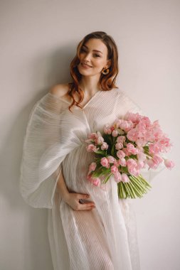 Beyaz elbiseli, lale desenli hamile kadın portresi.