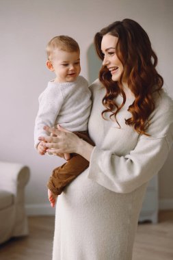 Mutlu hamile kadın ve küçük oğlu. Genç anne ikinci bebeğini bekliyor. Hamilelik ve aile imajı. Sıcak ve samimi bir sahne. Üst görünüm. 
