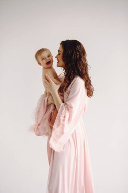 Güzel anne küçük kızına sarılıyor ve beyaz arka planda poz veriyor. Anne ve küçük kız. Aile kavramı. Aşk konsepti. Kadınlar Günü