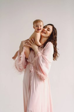 Güzel anne beyaz arka planda küçük kızıyla oynuyor. Anne ve bebek. Aile kavramı. Aşk konsepti. Kadınlar Günü