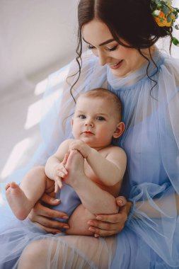 Sevgi dolu bir anne yeni doğmuş bebeğini taşıyor. Anne ve bebek güneşli yatak odasında oynuyorlar. Ebeveyn ve küçük çocuk evde dinleniyor. Aile birlikte eğleniyor. Çocuk bakımı, annelik kavramı