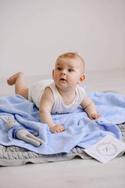 Yakışıklı bebek 8 numaralı kartın yanında yerde yatıyor. 8 aylık bir çocuk ısırıp oynuyordu. Mutlu çocukluk kavramı. Uzayı kopyala Mavi battaniye