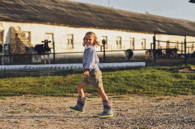 Yazın çiftlikte yürüyen gülümseyen çiftçi çocuk. Kırsalda mutlu bir çocukluk. Mutlu yazlar, açık hava yaşam tarzı