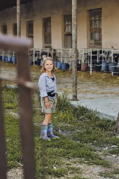 Çiftçi çocuğun yazın bir çiftlikte oynadığı dikey fotoğraf. Çocuk ve hayvan dostluğu. Mutlu bir çocukluk. Mutlu yazlar, açık hava yaşam tarzı