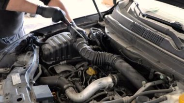 Tamirci elinde tornavidayla araba motorunun hava filtre borusunu vidalıyor. araç bakım servisi