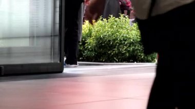 İnsanlar otomatik kapıların önünde hızla yürüyorlar. Ofis binasına ve alışveriş merkezine girip çıkan insanlar..